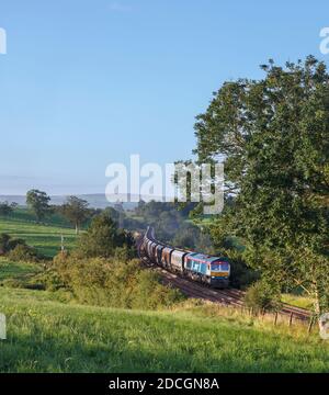 GB Railfeight classe 66 locomotiva 66747 passando Coniston Cold in La valle dell'Aire con un treno merci di aggregati vuoti tramogge Foto Stock