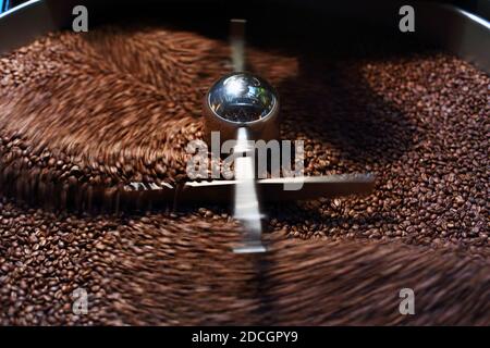 Appena il caffè torrefatto in grani da un grande torrefattore essendo versato nel cilindro di raffreddamento. Motion Blur per i fagioli. Foto Stock