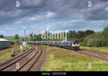 GB Railfeight classe 66 locomotiva 66747 passando Hellifield in Valle dell'Aire con un treno merci di tramogge aggregate Foto Stock