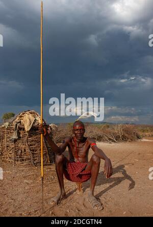 Ritratto di un uomo della tribù dei Pokot seduto sul suo cuscino di legno che tiene una lancia, Baringo County, Baringo, Kenya Foto Stock