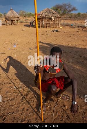 Ritratto di un uomo della tribù dei Pokot seduto sul suo cuscino di legno che tiene una lancia, Baringo County, Baringo, Kenya Foto Stock