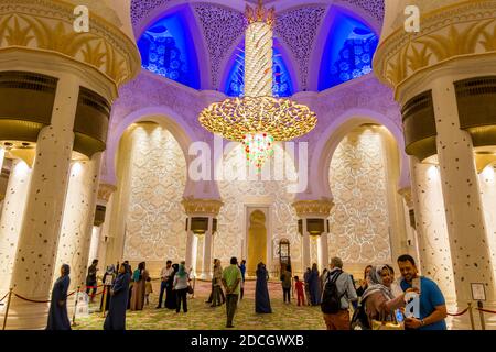 Molti turisti all'interno della Grande Moschea di Abu-Dhabi, negli Emirati Arabi Uniti, chiamata anche Grande Moschea dello Sceicco Zayed, ispirata alla moschea persiana, Mughal e moresca Foto Stock