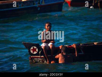 Ragazzi che giocano su una barca e in mare, Lamu County, Lamu, Kenya Foto Stock