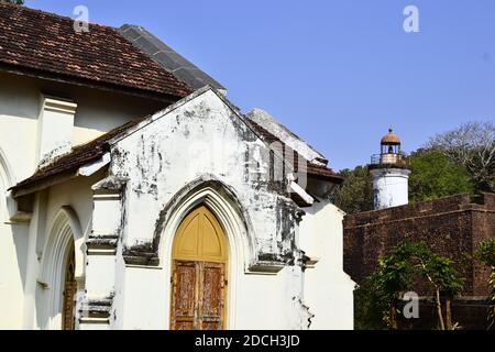 Vecchia chiesa cattolica vicino Thalassery Fort. Faro coloniale e fortezza muro sullo sfondo. Kerala, India Foto Stock