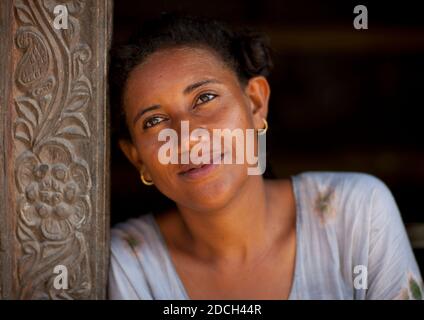 Donna keniota appoggiata su una colonna di legno intagliato, Lamu County, Lamu, Kenya Foto Stock