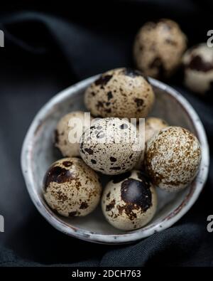 Uova di quaglia in ciotola bianca su sfondo nero, uova di quaglia, mucchio di uova di quaglie in ciotola, uova macchiate, uova macchiate in ciotola, uova di quaglia su sfondo scuro Foto Stock