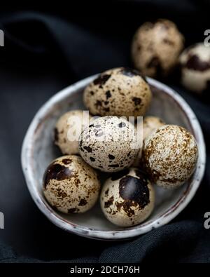 Uova di quaglia in ciotola bianca su sfondo nero, uova di quaglia, mucchio di uova di quaglie in ciotola, uova macchiate, uova macchiate in ciotola, uova di quaglia su sfondo scuro Foto Stock