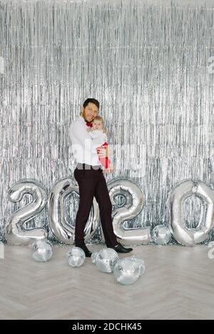 Felice padre tiene suo figlio tra le braccia e incontra il nuovo anno, vedendo fuori il vecchio Foto Stock