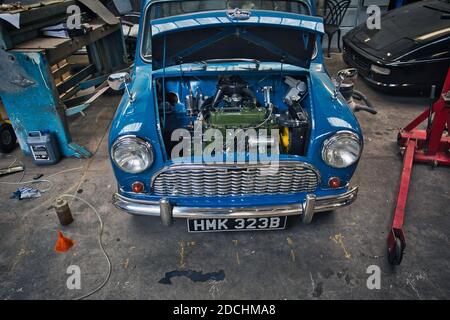 L'auto Morris degli anni '60 è stata parzialmente smontata/spogliata per il restauro in una garagewith domestica con cofano aperto che mostra il motore Austin-Morris SERIE A. Foto Stock