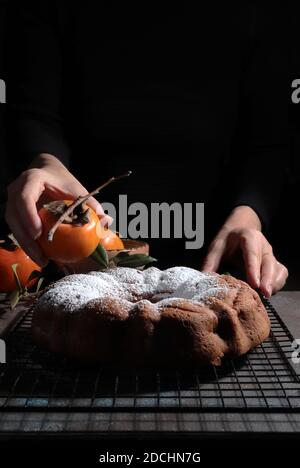 Torta di persimmon al cioccolato fatta in casa con zucchero in polvere. Sfondo scuro Foto Stock