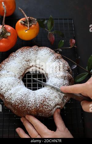 Torta di persimmon al cioccolato fatta in casa con zucchero in polvere. Sfondo scuro Foto Stock