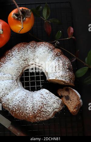 Torta di persimmon al cioccolato fatta in casa con zucchero in polvere. Sfondo scuro Foto Stock