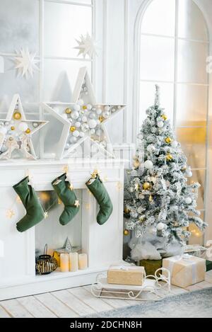 Eleganti decorazioni natalizie del soggiorno in tonalità oro e argento. Un grande albero di Natale splendidamente decorato si trova nella stanza accanto al fuoco Foto Stock