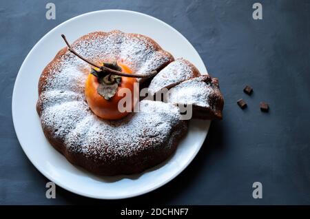 Torta di persimmon al cioccolato fatta in casa con zucchero in polvere isolato su sfondo grigio. Vista dall'alto. Foto Stock