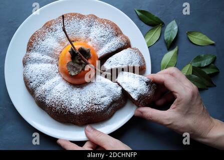 Torta di persimmon al cioccolato fatta in casa con zucchero in polvere isolato su sfondo grigio. Vista dall'alto. Foto Stock