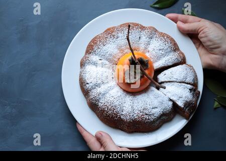 Torta di persimmon al cioccolato fatta in casa con zucchero in polvere isolato su sfondo grigio. Vista dall'alto. Foto Stock