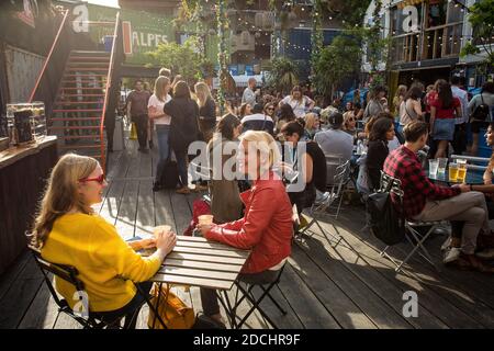 Le persone godono di un drink a Brixton pop, pop up contenitore bar e ristoranti a Brixton, London, Regno Unito Foto Stock