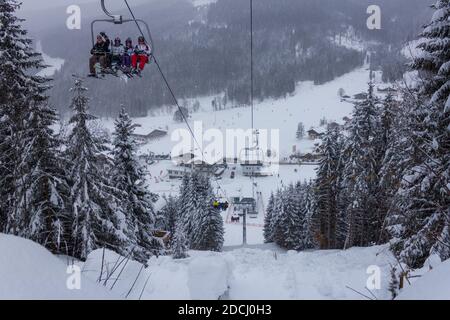 Paesaggio invernale innevato con gruppo di sciatori che durante le vacanze prendono la seggiovia Grossbergbahn (Filzmoos, provincia di Salisburgo, Austria) Foto Stock