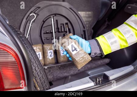 La polizia impadronirsi di droga nel bagagliaio di un veicolo durante arresto del traffico Foto Stock