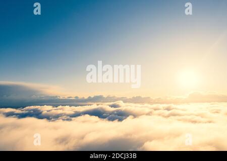 Vista aerea aurea alba su nuvole in cielo blu. Vista aerea dall'alto nuvoloso. Texture di nuvole. Vista dall'alto. Alba arancione o tramonto su nuvole Foto Stock