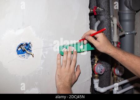 installazione di prese elettriche aggiuntive nella parete del bagno. L'elettricista misura lo spazio. Costruzione e riparazione. Foto Stock