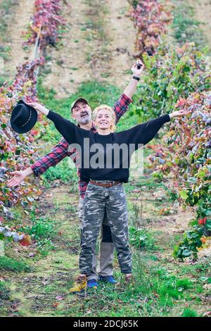 Giovane coppia matura di agricoltori in un vigneto contadino scherzando. Foto Stock