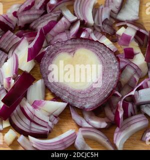 cipolla rossa tagliata a fette a forma di cuore su tritare in legno scheda Foto Stock