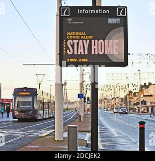 Traffico stradale che passa National Covid Alert segnale elettronico tra principale strada e tram Foto Stock