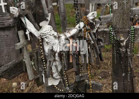 Figura spezzata di Gesù Cristo decorata con piccole croci di legno sulla collina delle croci vicino a Šiauliai in Lituania. Il più importante luogo di pellegrinaggio lituano si trova a circa 12 km dalla città di Šiauliai. Nessuno ha mai provato a contare quante croci grandi e piccole sono effettivamente installate sulla collina, ma si ritiene che ci siano almeno duecentomila croci qui. E ogni giorno decine o addirittura centinaia di nuove croci vengono aggiunte da pellegrini provenienti da tutto il mondo. Foto Stock