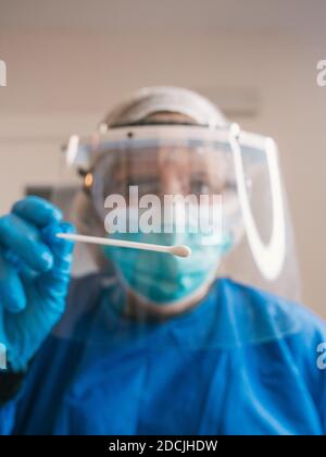 Ritratto donna professionista sanitario con protezione contro covid 19 con maschera, capello e occhiali facendo test pcr Foto Stock