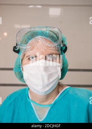 Ritratto donna professionista sanitario con protezione contro covid 19 con capello, maschera e occhiali Foto Stock