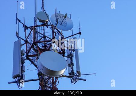 Torre per telecomunicazioni con trasmettitori 4G, 5G. Stazione base cellulare con antenne di trasmissione su una torre per telecomunicazioni contro il cielo blu Foto Stock