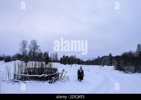 Lo scarrecrow fatto a mano su un campo innevato nel villaggio in inverno. Foto Stock