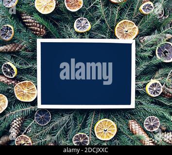Tavola vuota incorniciata su rami di abete verde decorata con fette aranciate e coni. Natale e Capodanno vintage festa invernale comp Foto Stock