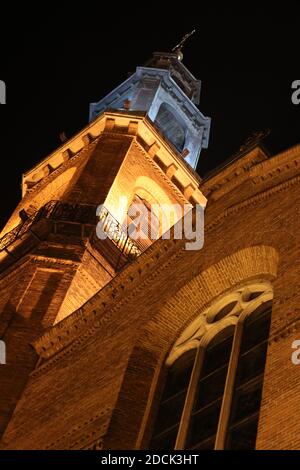 Vista dal basso su una torre della chiesa evidenziata di notte Foto Stock