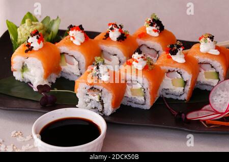 involtini di sushi giapponesi con tonno, formaggio cremoso, salmone e salsa di soia Foto Stock