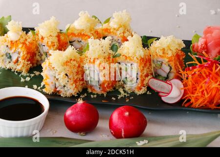 involtini di sushi giapponesi con gamberi di tempura, formaggio cremoso, salmone e salsa di soia Foto Stock