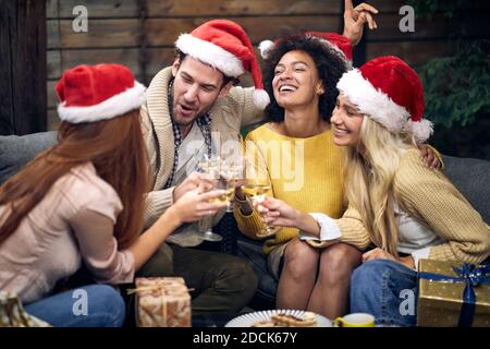 Gruppo di giovani felici che festeggiano insieme Natale o Capodanno; concetto di festa della casa Foto Stock