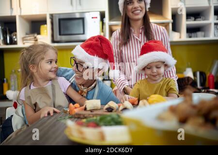 Nonna e madre che si godono con i bambini in un'atmosfera festosa in cucina per un Natale. Natale, famiglia, insieme Foto Stock