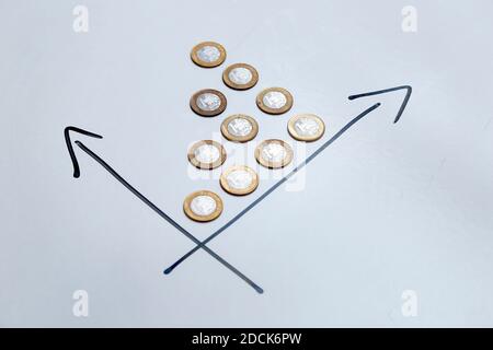 monete su sfondo bianco e frecce direzionali che indicano la crescita del tempo e dei profitti - finanza, reddito e concetto di interesse. Foto Stock