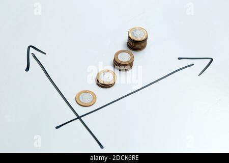 monete su sfondo bianco e frecce direzionali che indicano la crescita del tempo e dei profitti - finanza, reddito e concetto di interesse. Foto Stock