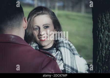 La giovane ragazza sorridente si trova di fronte al ragazzo nel parco. Effetto blu freddo aspetto pellicola Foto Stock