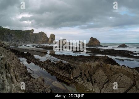 Una costa rocciosa e selvaggia con onde tempestose che colpiscono il shore Foto Stock