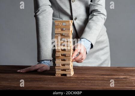 Uomo d'affari che rimuove il blocco di legno dalla torre Foto Stock