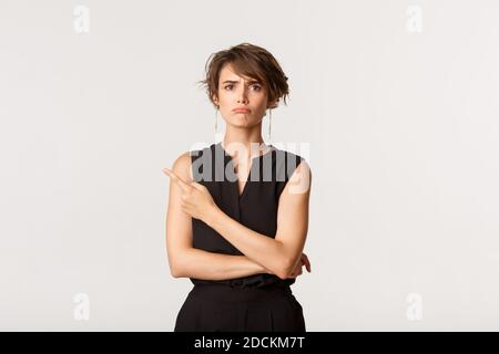 Ritratto di ragazza che si ribella in alto a sinistra, lamentando, in piedi su sfondo bianco Foto Stock