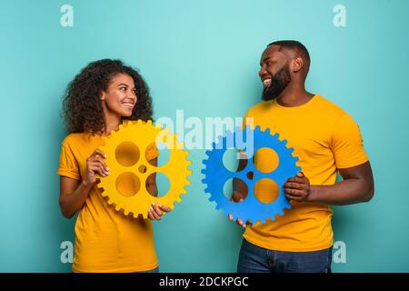 Coppia con ingranaggi in mano su fondo azzurro. Concetto di integrazione europea e il partenariato Foto Stock