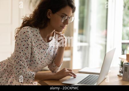 Giovane donna in occhiali che lavora su un computer portatile Foto Stock