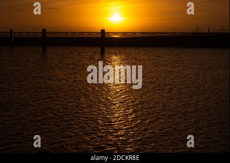 Hooksiel, Germania. 22 novembre 2020. Il sole sorge la mattina presto dietro il porto esterno di Hooksiel. Credit: Mohssen Assanimoghaddam/dpa/Alamy Live News Foto Stock