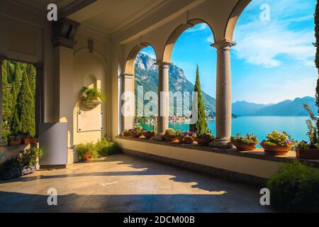 Splendido balcone decorato con fiori e oggetti ornamentali. Splendida vista dall'accogliente balcone con il lago di Como e le montagne, Varenna, Italia, Europe Foto Stock