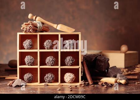 Tartufi di cioccolato con pezzi di cioccolato spezzati. Cioccolato, spezie e ingredienti su un tavolo marrone. Foto Stock